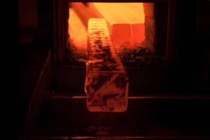 Aluminum billets inside an industrial furnace glowing red at high temperature