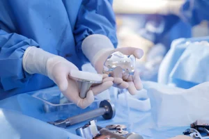 Surgeon holding knee replacement prosthesis components in a sterile orthopedic setting